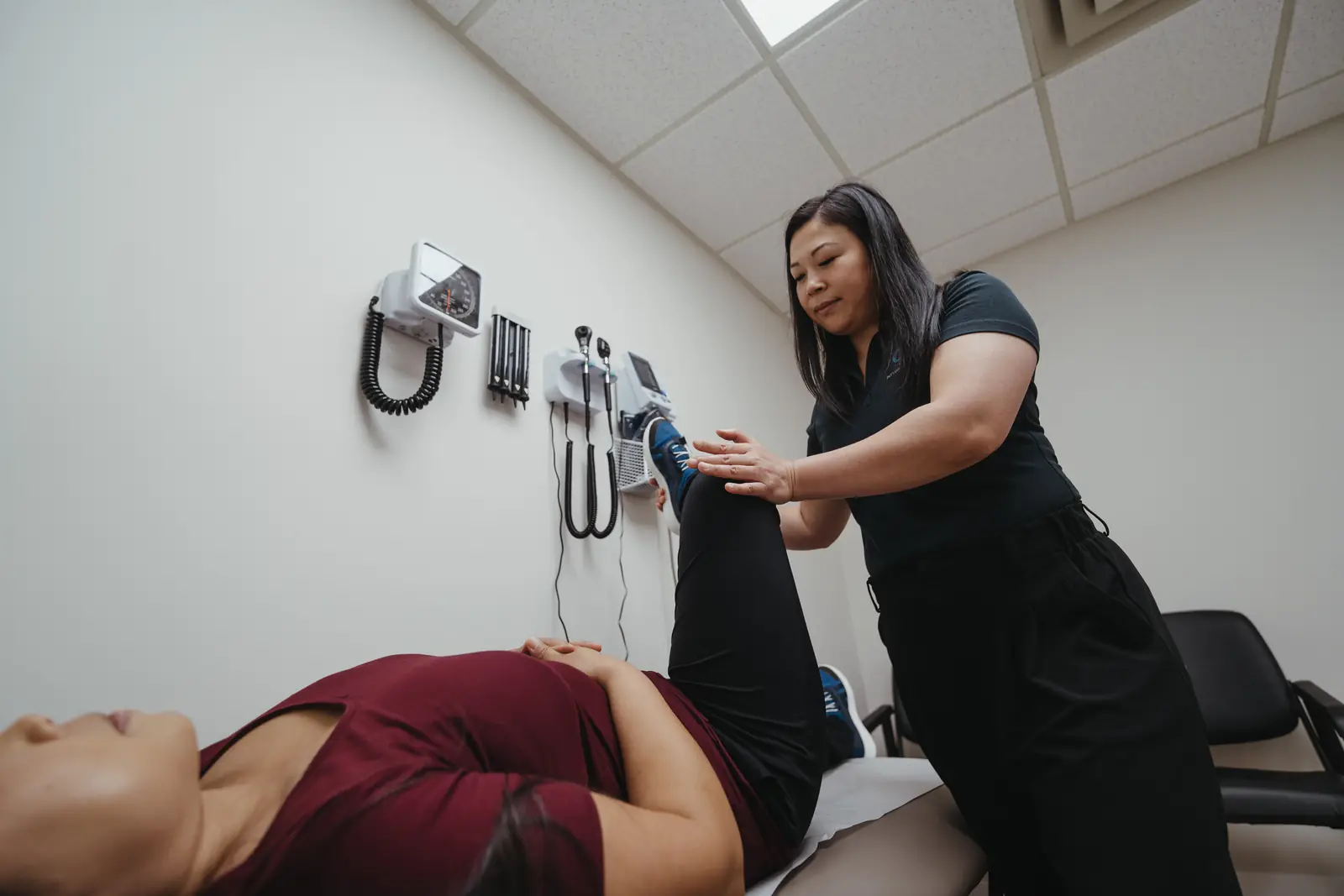 Physiotherapist An Luu assessing a patient's leg in a treatment room